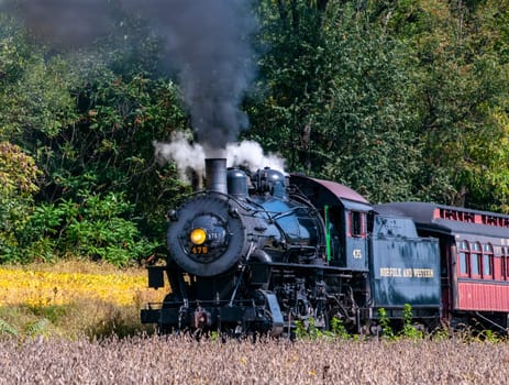 Strasburg, Pennsylvania, October 4, 2023 - A View of a Restored Steam Engine Pulling Passenger Coaches, Blowing Smoke on a Fall Day
