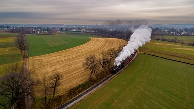 An Aerial View of a Steam Passenger Train Approaching Around a Curve Blowing Smoke on an Autumn Day