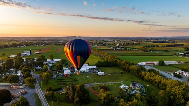 An Aerial View of a Multi-Colored Hot Air Balloon, Floating Over Pennsylvania Farmlands at Sunrise, on a Summer Day