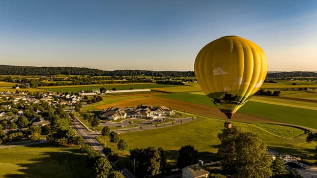 An Aerial View on a Yellow Hot Air Balloon Floating Over a Countryside Community, on a Beautiful Summer Day