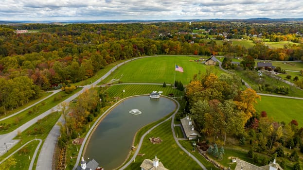 An Aerial View of Fall Countryside of Sun and Color with a Pond and American Flag on a Sunny Autumn Day