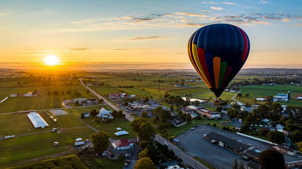 An Aerial View of a Multi-Colored Hot Air Balloon, Floating Over Pennsylvania Farmlands at Sunrise, on a Summer Day
