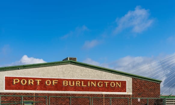 Sign of the Port of Burlington in Iowa besides the Mississippi river with suspension bridge behind