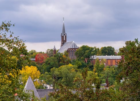 Unusual spire of St John Catholic church among fall trees in the city of Burlington in Iowa