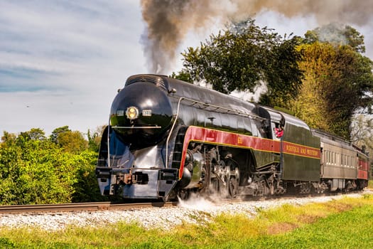 A View of a Steam Passenger Train Approaching Around a Curve, Traveling Thru Rural America, Blowing Smoke on a Summer Day