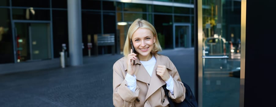 Close up portrait of young blond woman, walking on street and talking on mobile phone, chatting with friend on smartphone. Lifestyle and people concept