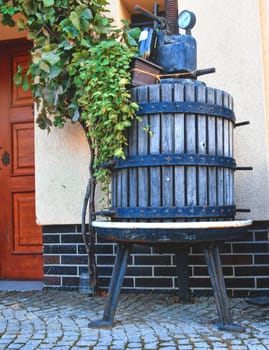 An old historic wine press. The press serves as a decoration and holds creeping plants.