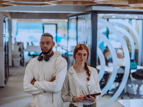 In a modern office African American young businessman and his businesswoman colleague, with her striking orange hair, engage in collaborative problem-solving sessions.