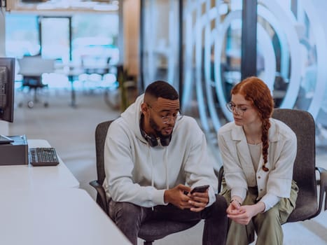 In a modern office African American young businessman and his businesswoman colleague, with her striking orange hair, engage in collaborative problem-solving sessions.