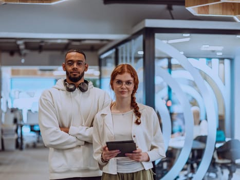 In a modern office African American young businessman and his businesswoman colleague, with her striking orange hair, engage in collaborative problem-solving sessions.