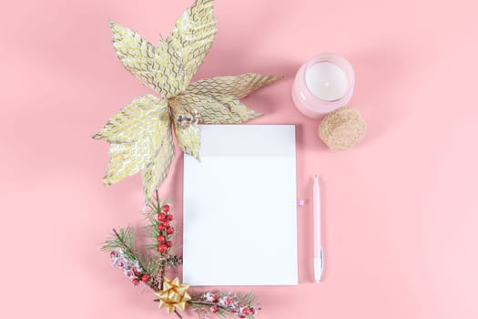 Open blank notebook with space for texat, wood numbers 2022, pen, candle and christmas decoration on pink background, top view to rupture plan.