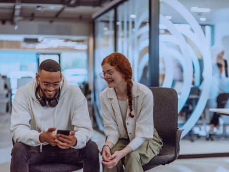 In a modern office African American young businessman and his businesswoman colleague, with her striking orange hair, engage in collaborative problem-solving sessions.