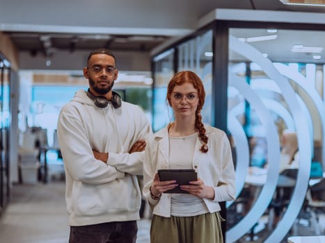 In a modern office African American young businessman and his businesswoman colleague, with her striking orange hair, engage in collaborative problem-solving sessions.