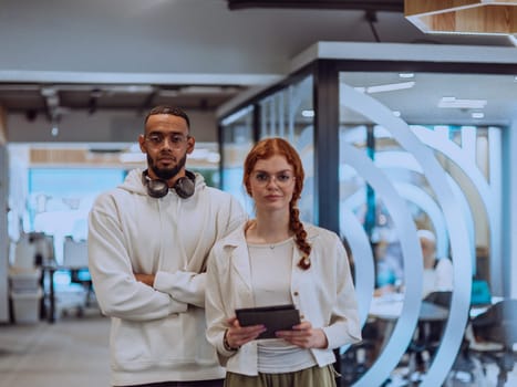 In a modern office African American young businessman and his businesswoman colleague, with her striking orange hair, engage in collaborative problem-solving sessions.