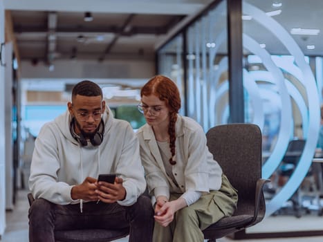 In a modern office African American young businessman and his businesswoman colleague, with her striking orange hair, engage in collaborative problem-solving sessions.