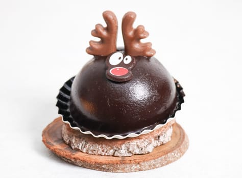 One chocolate cake deer on wooden cuts lies on a white cement table, close-up side view.