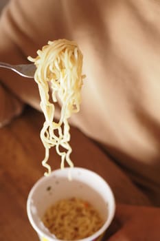 women eating instant noddles at home .