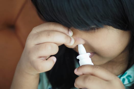 close up of sick child using nasal medicine spray.