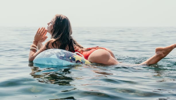 Woman summer sea. Happy woman swimming with inflatable donut on the beach in summer sunny day, surrounded by volcanic mountains. Summer vacation concept