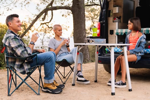 family camping in the countryside with their camper van, concept of active tourism in nature and outdoor activities with children