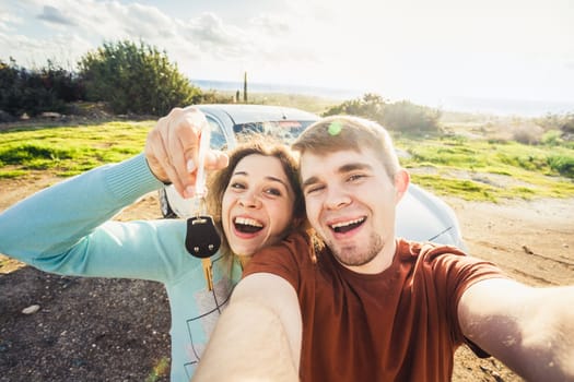 portrait of happy beautiful couple showingh the keys standing near the car