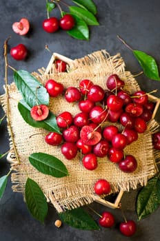Cherry summer background. A large number of cherries with leaves on the table, on a black background.
