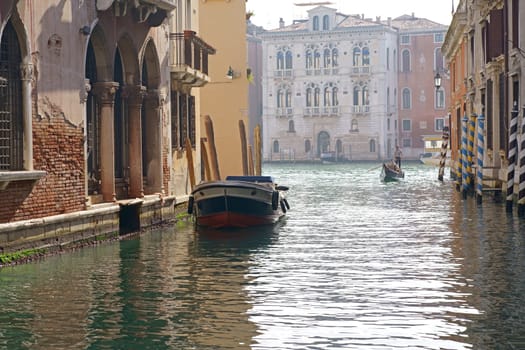 Sunny channel in Venice with boats parked around