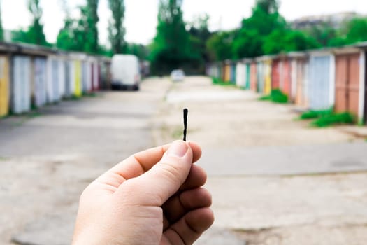 A match, a hand with matches against the background of old garages in city.