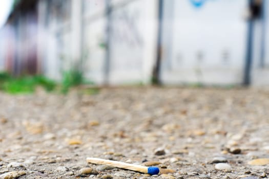 A match, a hand with matches against the background of old garages in city.