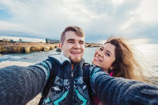 Young happy couple is taking selfie photo on vacation near sea
