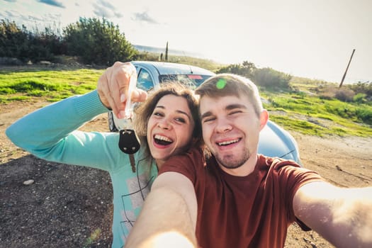 portrait of happy beautiful couple showingh the keys standing near the car.