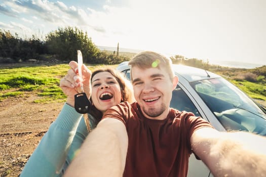 portrait of happy beautiful couple showingh the keys standing near the car.