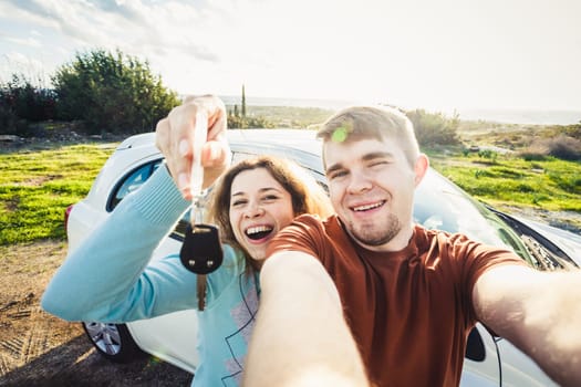 portrait of happy beautiful couple showingh the keys standing near the car.