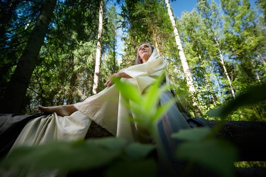 Beautiful seductive dryad. Pagan spirit of forest. Portrait of beautiful dryad. Fairy who loves nature in beautiful green summer forest. Concept of environmental friendliness and caring for nature