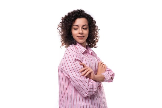portrait of a 30 year old authentic slim curly brunette model woman wearing a pink shirt.