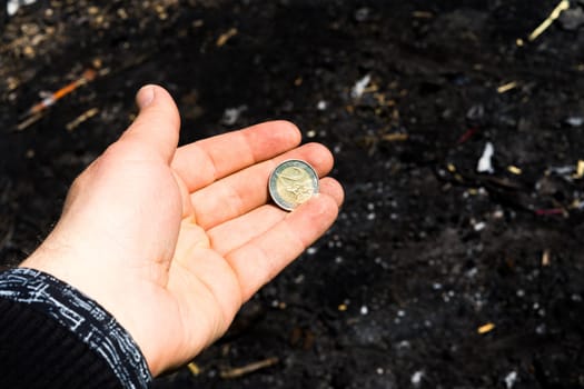 Coin and banknotes at black hot coal among ashes. Currency devaluated, finance and business concept