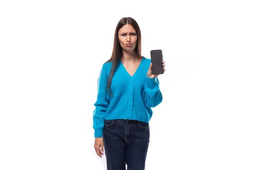 sad young brunette lady dressed in blue casual buttoned cardigan showing mobile phone screen.