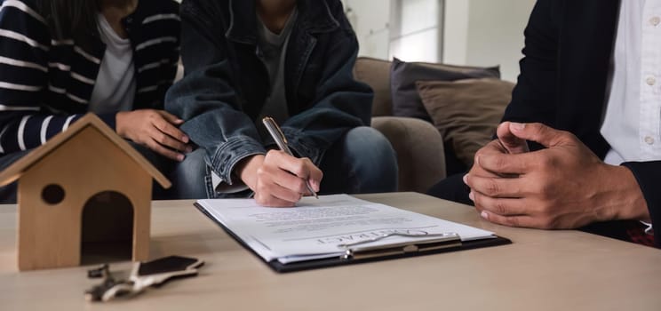 Real estate agents present and advise clients on the decision to sign a home purchase agreement form. Offering mortgage loans and home insurance.