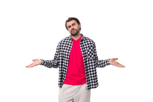 Portrait of a caucasian handsome man with a beard and styled hair stands thoughtfully on a white background with copy space.