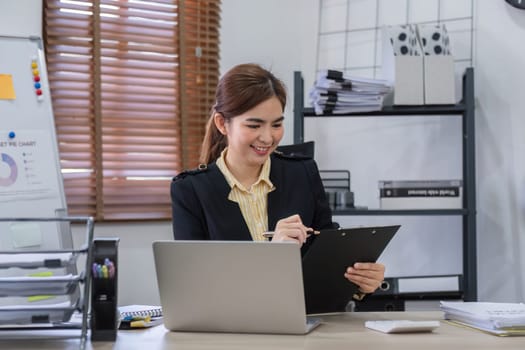 Businesswoman uses laptop to do finance, mathematics on wooden table in office and business background, tax, accounting, statistics and analytical research concept..