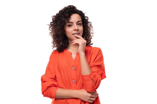 young stylish curly caucasian brunette woman dressed in orange blouse.