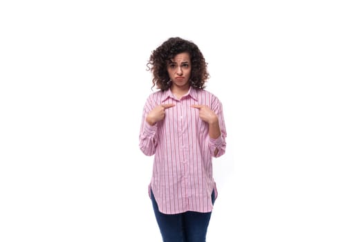 young well-groomed brunette woman in a pink shirt with a grimace isolated on white background.