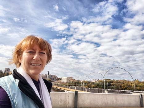 Relaxed mature caucasian female looking at camera and making selfie outside. Positive senior woman against city street background. Adult middle agged girl Blogger posing and taking photo for the internet