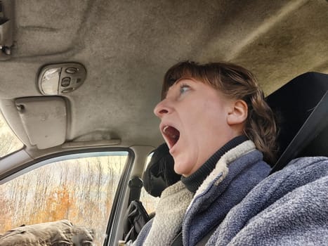 Terrified female driver a second before the accident. Scared middle-aged adult woman holds the steering wheel of car. Frightened Lady girl who is owner or rent a car for travel