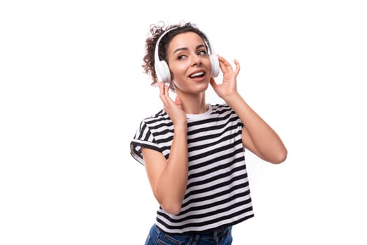 young positive curly brunette woman music lover in a striped casual t-shirt with headphones dancing.