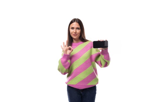 e-business concept. 35 year old feminine model woman dressed in a pink pullover demonstrates the screen of a mobile phone.