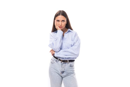 young upset european business lady with long black hair dressed in a blue blouse on a white background with copy space.