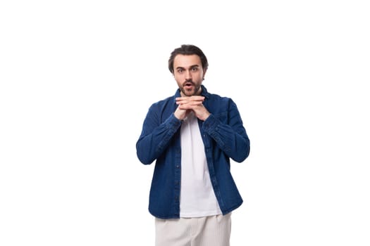 young slender handsome brutal brunette caucasian guy in a denim shirt and light-colored trousers.