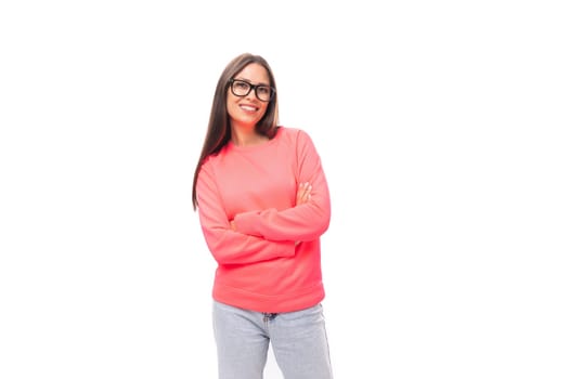 beautiful well-groomed young brunette european woman in glasses dressed in a pink sweatshirt on an isolated white background with copy space.