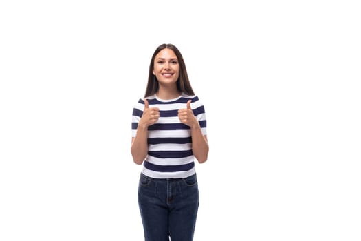 A slender young brunette caucasian woman with light make-up dressed in a striped T-shirt and jeans shows class with her hands.